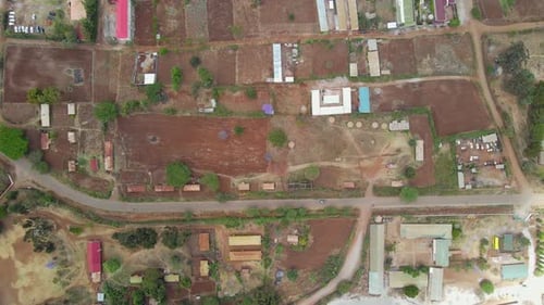 Aerial view of a town and sunlit fields, golden hour in rural Africa - tracking, drone shot. Green b