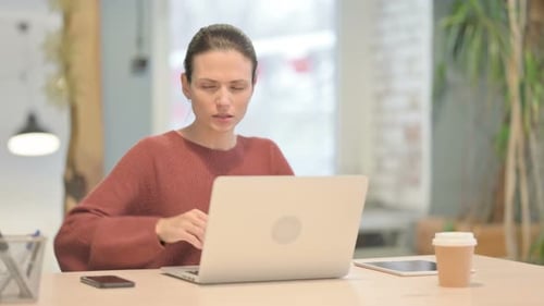 Woman Experiencing Back Pain While Working at Laptop