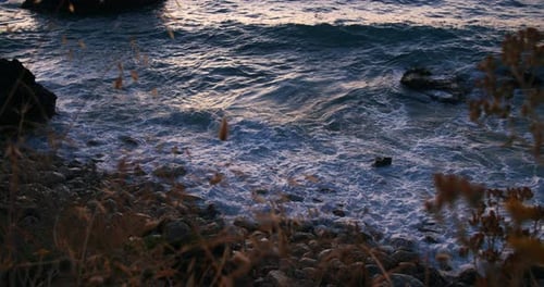 Beautiful slow motion of sea waves in the evening. Close-up of waves with foam. Stony rocky beach