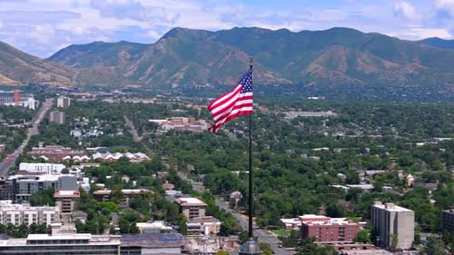 American Flag Waving over City with Mountain Backdrop