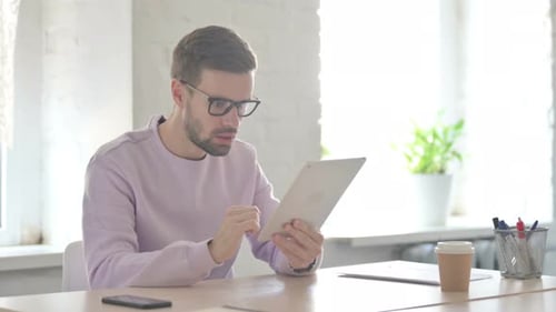 Young Man Having Loss on Tablet in Office