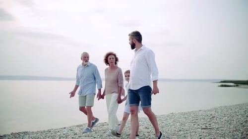 A Multigeneration Family On A Holiday Walking By The Lake, Holding Hands.