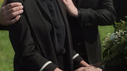 Unrecognizable Widow Being Supported by Close Friend at Outdoor Funeral