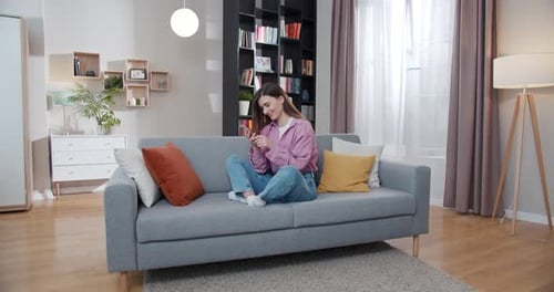 Woman Using Cell Phone on Couch at Home