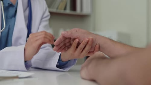 Die Hände des Arztes in Nahaufnahme berühren die Hand des Patienten zur Unterstützung. Fröhlich bei der Behandlung und Heilung von Krankheiten.
