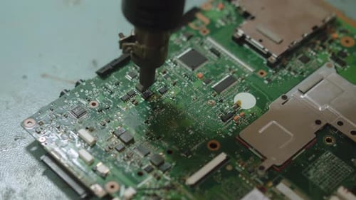 Mitarbeiter im Servicecenter für Elektronisch Reparaturen beim Löten von Leiterplattenkomponenten mit einem Techniker für Heißluftgebläse