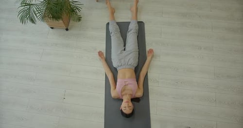 Athletic Young Woman Lying on the Gray Mat Relaxing After Exercise View From Above