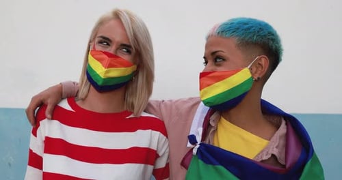 Two Young Women with Rainbow Flag Wearing Masks