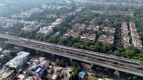 Aerial View of Modern Metro Train Passing Through Lush Cityscape