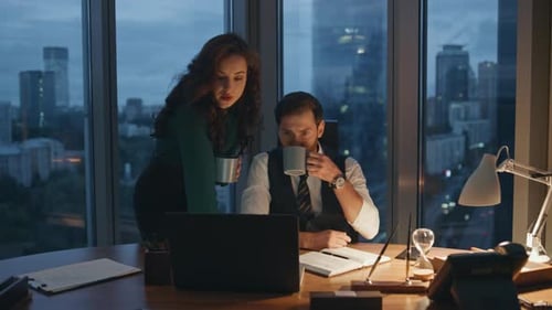 Busy business partners drinking coffee working late evening at office