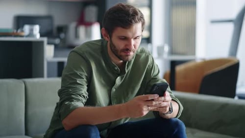 Young Adult Man Using Smartphone on Couch