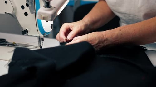 Close Up in a Sewing Workshop on a Machine the Old Seamstress Master Makes Cut on a Black Fabric