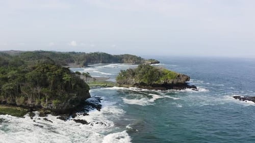 Scenic view of natural tropical coastline with crashing waves at the shore. Panoramic aerial shot.