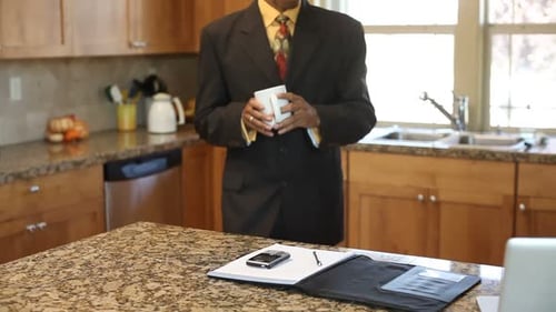 Businessman drinks coffee in kitchen before work
