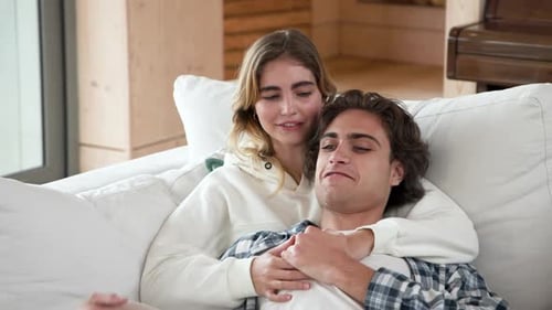 Couple relaxing on cozy sofa, sharing tender moment at home