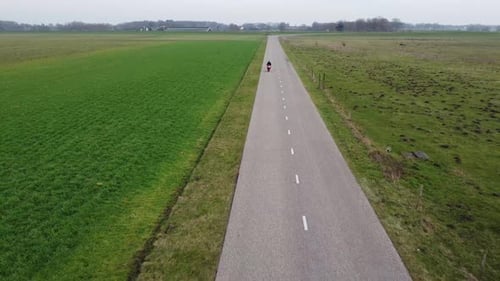 Two shots of a motorcyclist driving down a small road in nature.