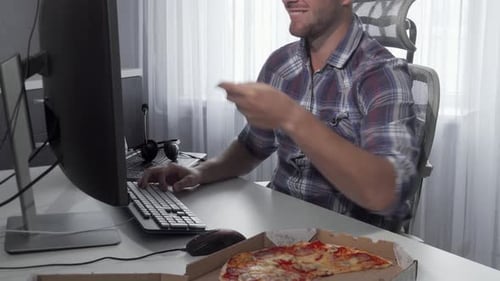 Young Adult Working and Eating Pizza at Desk