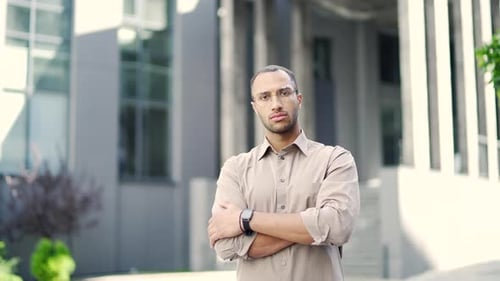 Young Man Standing with Arms Crossed Outside Building