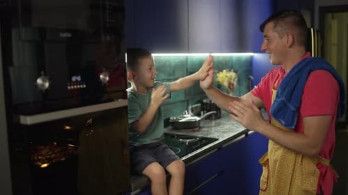 Father and Son Play Hand-Clapping Game in Kitchen
