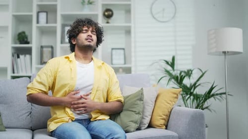 Young Man Experiencing Abdominal Pain on Sofa