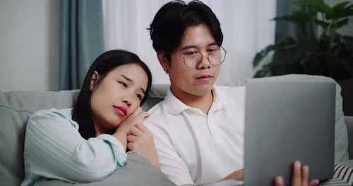 Couple Relaxing Together Using Laptop on Couch Indoors