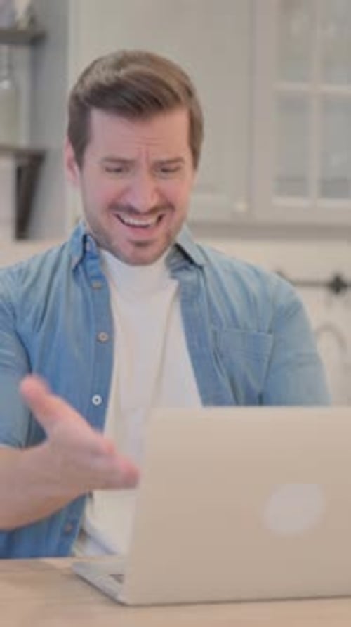 Frustrated Man Reacting to Content on Laptop Indoors