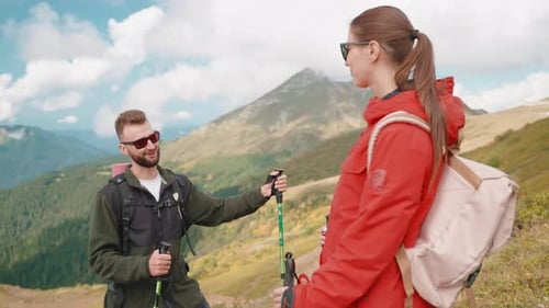 Couple of Young Hikers Smiling Talking Resting From Trekking on Mountain Slope