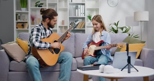 Man and Girl Play Guitars Together at Home