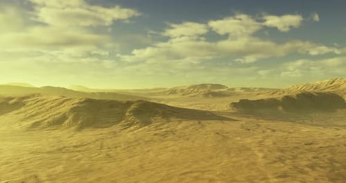 Weite Wüstenlandschaft unter klarem Himmel mit weichen Wolken und fernen Hügeln