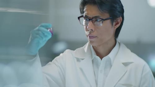 Scientist Inspects Pink Liquid in Laboratory Vial