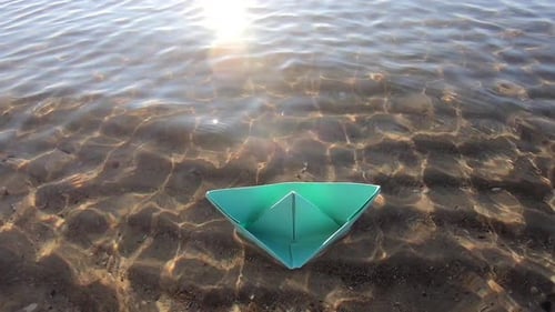 Small Green Paper Boat Floats Swaying on Sea Waves with Transparent Clear Water