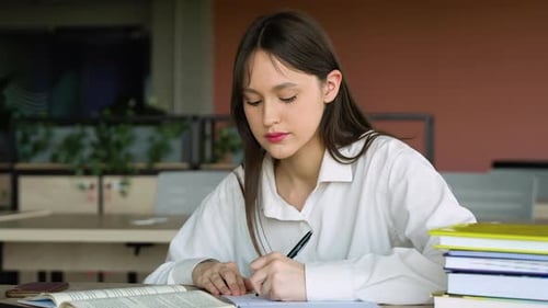 Teenage Girl Making Notes in Library Preparing to the Exams Back to School