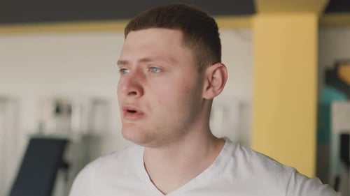 Exhausted Male Athlete Catches His Breath After a Rigorous Workout at the Gym
