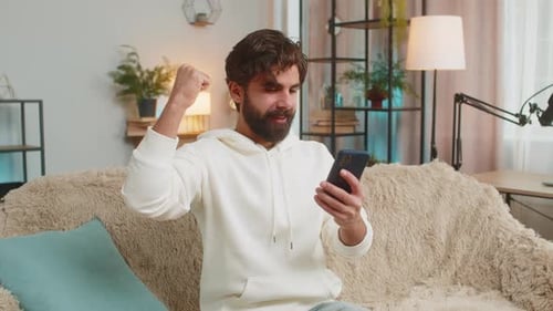 Excited Man Celebrates Success Using a Mobile Phone