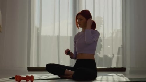 Woman Putting in Earbuds Before Home Workout