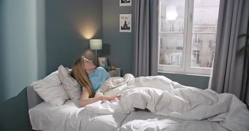 Blonde Woman Waking Up and Stretching in Bed