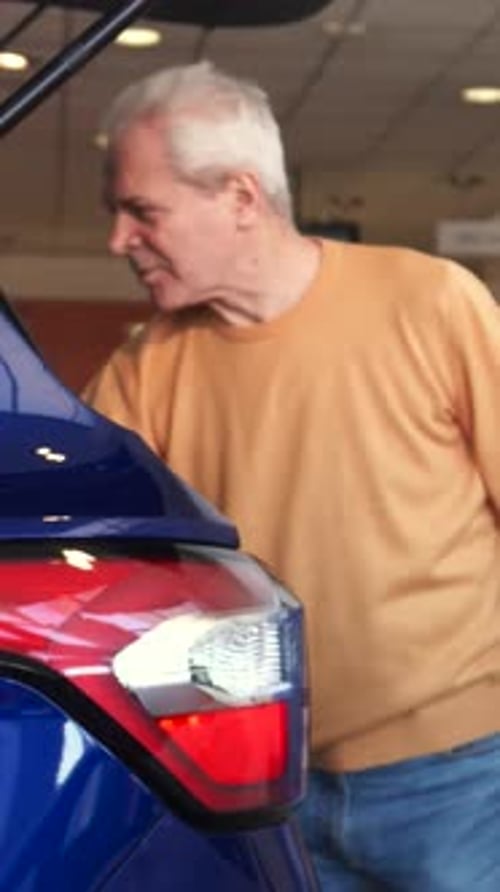 Senior Man Excitedly Opens Car Trunk at the Dealership