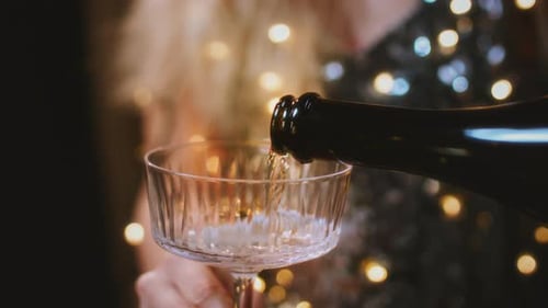 Mãos femininas seguram copos redondos para mulheres com champanhe em um vestido cintilante