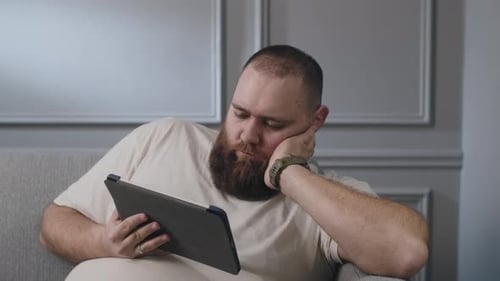 Man Relaxing at Home Looking at Tablet