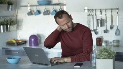 Man Working on Laptop with Neck Pain at Home