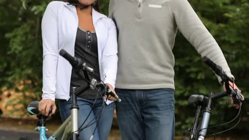Cheerful caucasian couple smiling during bicycle ride in mountain park