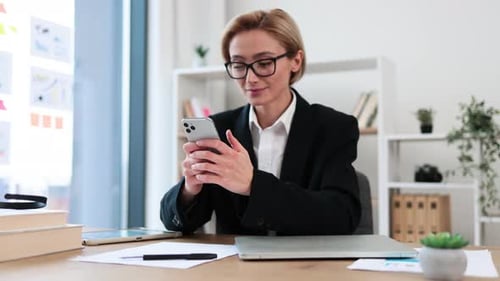 Professional Woman Using Smartphone in Modern Office Environment and Smiling