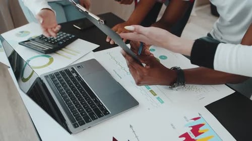 Team von gemischtrassigen Unternehmensmitarbeitern diskutiert begeistert am Tisch drinnen über Arbeitsprojekt