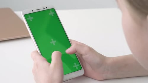 Mädchen hält ein Greenscreen-Telefon in ihren Händen und tippt eine Nachricht in sozialen Medien