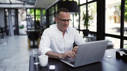 Adult Man Working on Laptop in Urban Cafe