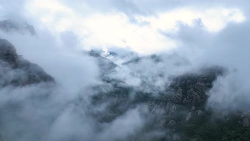 Misty mountain landscape at dawn with clouds rolling over peaks