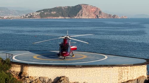 Vidéo aérienne de l'héliport côtier avec un hélicoptère rouge et un paysage pittoresque