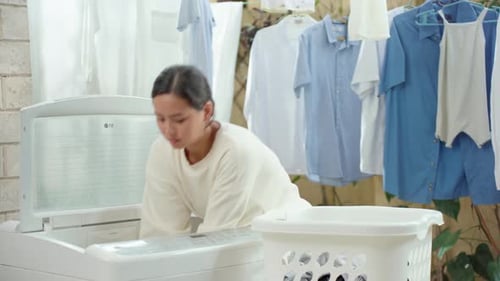 Young Housewife Taking Out Clothes From Washing Machine. Medium Shot