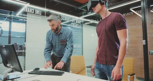 NEW YORK April 5 2017Two Attractive Men Testing Virtual Reality Glasses Man Typing on Computer