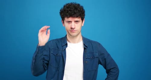 Man with Curly Hair Shrugs Shoulders on Blue Background